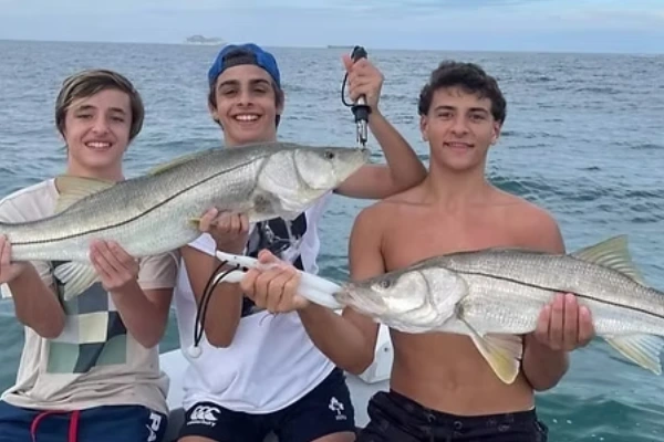 Three anglers celebrate together after Miami Offshore Fishing Charters with Fetched Up Charters.