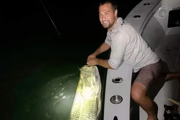 An angler stands in the water holding a fish after Biscayne Bay Fishing Charters with Fetched Up Charters.